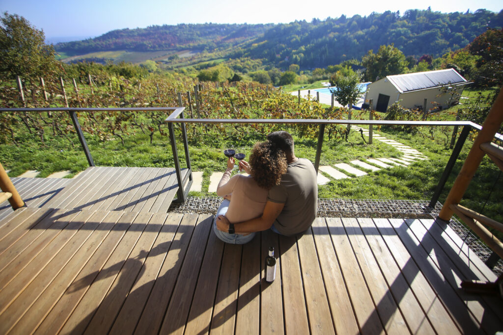 young couple sat on a deck overlooking a winery